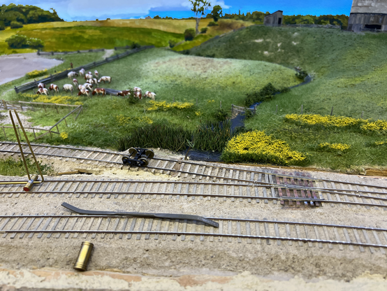 Model railroad scene with rifler file, roller gauge, loose test truck and track twist gauge all over the track