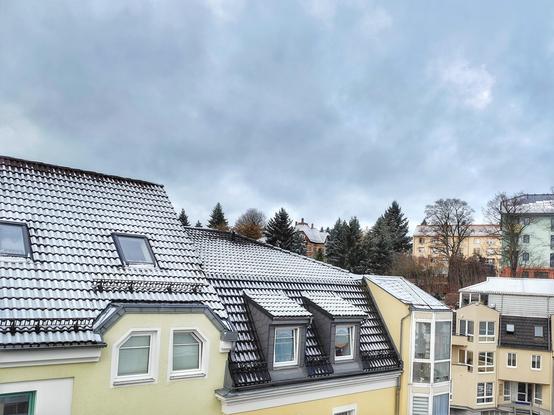 Hausdächer mit einer dünnen Schneeschicht bedeckt. Der Himmel grau mit einem Hauch von Blau.