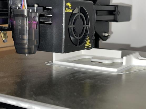 close up of a 3D printer head printing a while object on the printbed