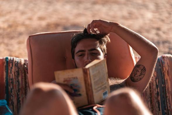 A person with a tattoo reading a book.
