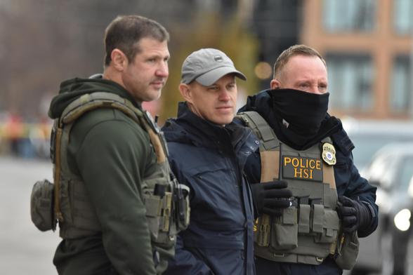 Three Federal agents, one masked, in tactical gear.