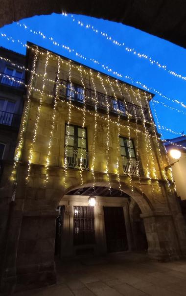 A historic stone building is adorned with cascading white fairy lights, creating a festive glow against the deep blue twilight sky.
#laureanoaraujo #santiagodecompostela #galiza
Santiago de Compostela, 18 de novembro de 2025