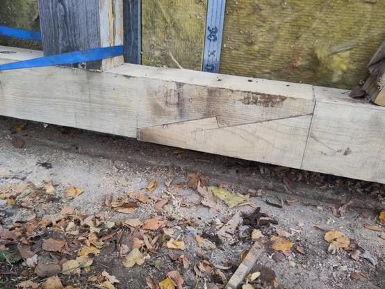 Aufnahme einer ausgetauschten Eichen-Fachwerkschwelle auf einer Baustelle. Die Enden von zwei Schwellen, die längs miteinander verbunden wurden, wurden schräg angesägt und haben eine Art Haken, mit dem die beiden Schwellen ineinandergreifen, sodass sie sich nicht in Längsrichtung gegeneinander verschieben können.
Auf dem Holz sind noch Bleistiftstriche zu erkennen, die bei der Ausarbeitung der Verbindung gemacht wurden. Die Verbindung passt sehr genau.