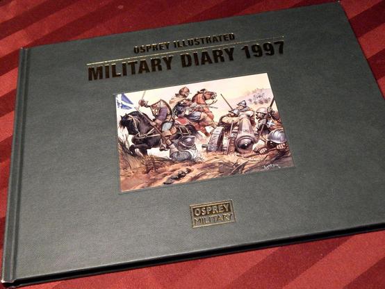 Cover of a landscape-formatted calendar diary, the Osprey Illustrated Military Diary 1997, a green hardcover with shiny letters (that turned up dark in this photo) and a small inset bit of artwork showing a medieval combat scene from an Osprey military history book.