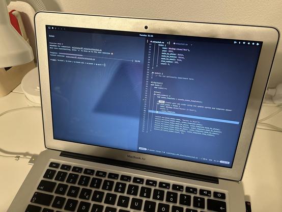 A 2017 MacBook Air displays a programming code editor with Rust code. The code includes a struct definition and a main function for creating an order template. In the background, a desk lamp and other items are visible.