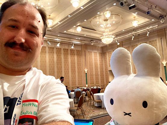 Matthew and Miffy in DrupalCon Nara t-shirt standing in front of the contribution room