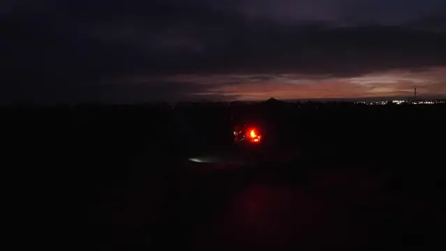 Beleuchtetes Fahrrad auf einem dunklen Radweg. Im Hintergrund der Vulkankegel des Desenbergs vor der Morgendämmerung