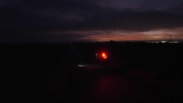 Beleuchtetes Fahrrad auf einem dunklen Radweg. Im Hintergrund der Vulkankegel des Desenbergs vor der Morgendämmerung