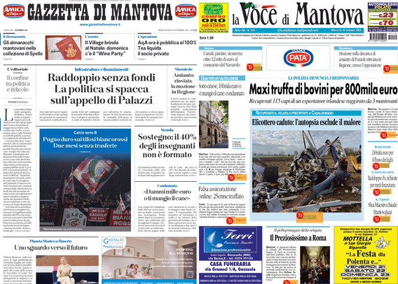 Due prime pagine di giornali locali visualizzate su uno schermo in un ambiente buio. A sinistra c’è “Gazzetta di Mantova” e a destra “La Voce di Mantova”. Entrambe le pagine mostrano articoli con titoli principali, spazi pubblicitari e immagini di notizie locali. Alcuni titoli principali sono leggibili: sulla Gazzetta di Mantova si legge “Raddoppio senza fondi La politica si spacca sul rimpallo di Palazzi”, mentre sulla Voce di Mantova il titolo principale è “Maxi truffa di bovini per 800mila euro”. Sono visibili immagini di cronaca e piccoli riquadri pubblicitari colorati.  .