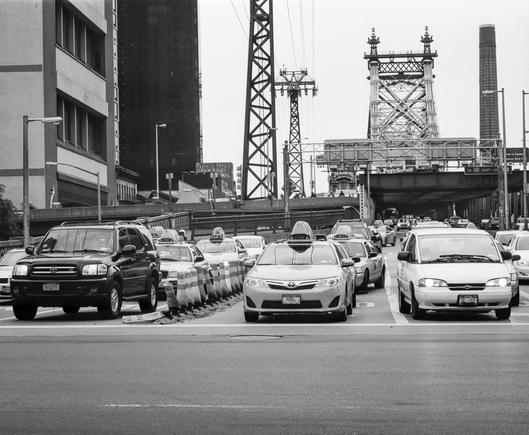Black and white photo of traffic leaving the 59th Street Bridge, from the Manhattan side.