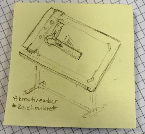 A hand-drawn sketch of a drafting table featuring a geometric tool, placed on a yellow sticky note. The image includes hashtags "#kreativember" and "#zeichenbrett" at the bottom. The background is a grid pattern.