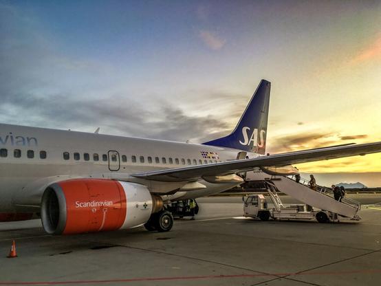A plane with the stairs attached and people boarding with the sunset in the background
