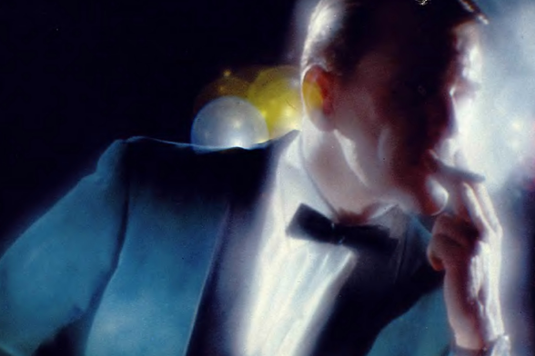 1964 Portrait of a Man in Blue Jacket and Bow Tie with Cigar, Under Glowing Light

The image features an individual captured under strong lighting effects which cast dramatic shadows across the scene.
The person is dressed formally in a blue jacket over what appears to be white attire, complemented by a black bow tie.
They are holding a lit cigar near their mouth, contributing to a sense of contemplation or leisure.
The background includes blurred bokeh lights suggesting an indoor setting with artificial lighting.