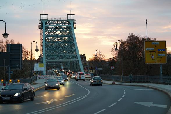 Blaues Wunder voller PKW, im Hintergrund Abendrot, Fahrbahn wegen Bauarbeiten verengt, viel zu viel Blech unterwegs