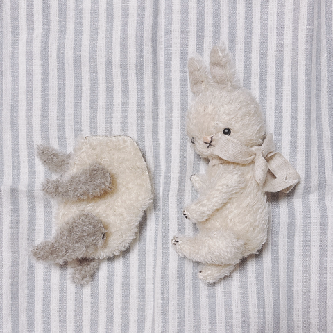 おなかが白で手足がグレーのモヘア生地のぬいぐるみパーツ、首にリボンを巻いた白いうさぎのぬいぐるみ