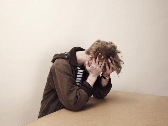 Photo of distressed-looking man with his head in his hands