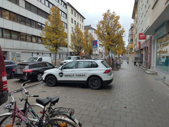 Ein Fahrschulauto steht auf einem Gehweg.
