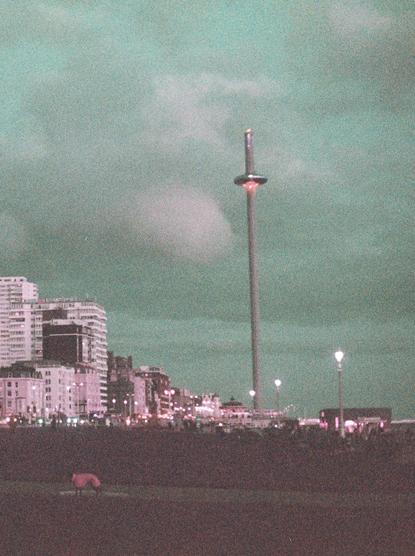 The centre of the frame is the I360, the buildings and lights are hued purple, and the sky is turquoise