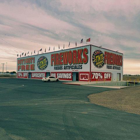 A white, boxy fireworks store with enormous signs advertising sales.
