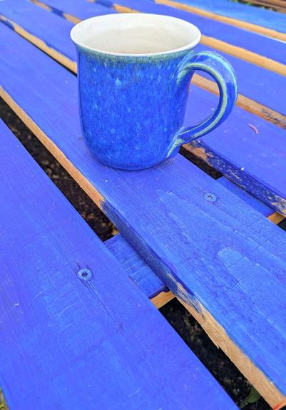 eine blaue Tasse steht auf blau gestrichenen Brettern