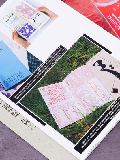 A spread of a visually striking design magazine displayed on grass, featuring colorful graphics and typography.