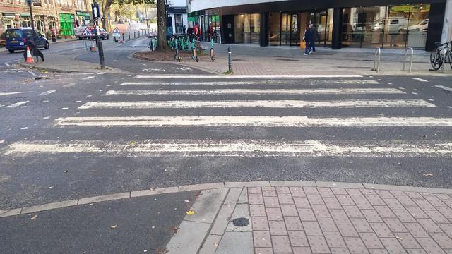 A two way cycle track left and footway right both crosa a side road over a zebra crossing wide enough to cover both.