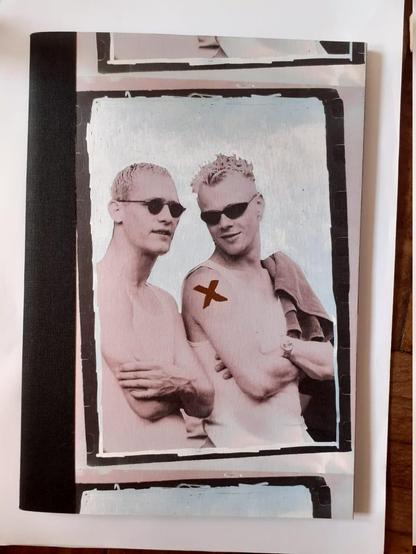 Capa do livro de fotos "Êxtase", de Nino Rezende.

A foto parece fazer parte de um conjunto de molduras, pois há pedaços de outras fotos acima e abaixo dela. 

A foto mostra dois jovens loiros sem camisa com óculos escuros. Um deles tem uma letra "X" vermelha no ombro e está virado para o outro, aparentemente falando alguma coisa.