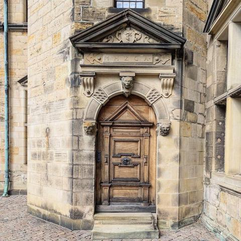 An elaborate, paneled historic castle door with carvings and stone accents, located in a corner of Hamlet's Castle in Helsingør.
