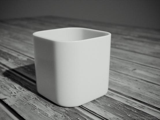 Square mug type container on a rough wooden bench.