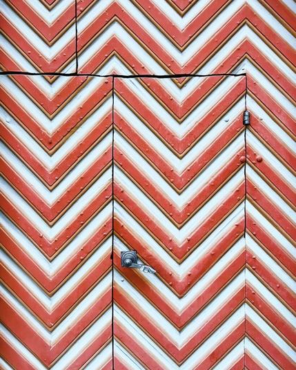 Eine Eingangstür aus Holz der St. Aegidiuskirche in Wiedenbrück. Man sieht ein rot weißes zickzackmuster.