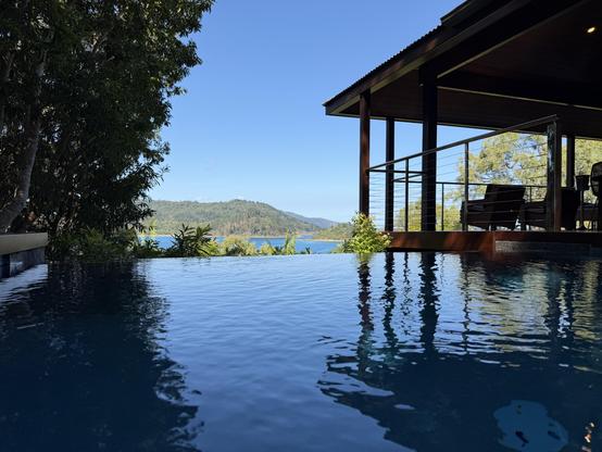 Photo looking out over our infinity pool to whitsunday island. The deep blue sky is reflected I. The surface of the water as is the roof of our pavilion.