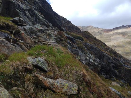 A rope-secured passage with rock-hewn metal steps.