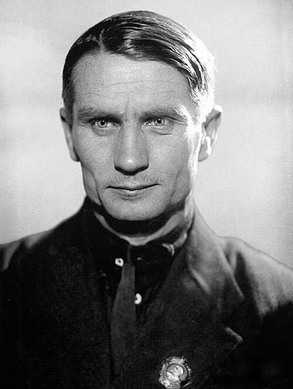 A black and white portrait of Trofim Lysenko, a Soviet biologist and agronomist, staring directly at the camera with a serious expression.