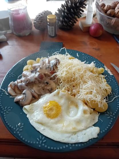 Œufs sur le plat, champignons à la crème et pâtes aux gruyère dans une assiette bleue