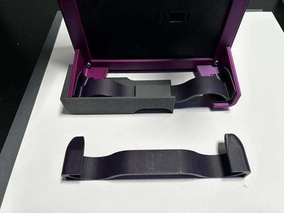 As described in the toot text.  Looking up at the underside of the air hockey table, the leg at one corner is held between the corner of the partial box and the compliant spring.  The spring is S shaped and has end caps that fit the inside of the leg.