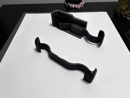 As described in the toot text.  Two 3D printed curved compliant springs.  One has been slid into a slot in the test piece that represents one corner of the gift box.