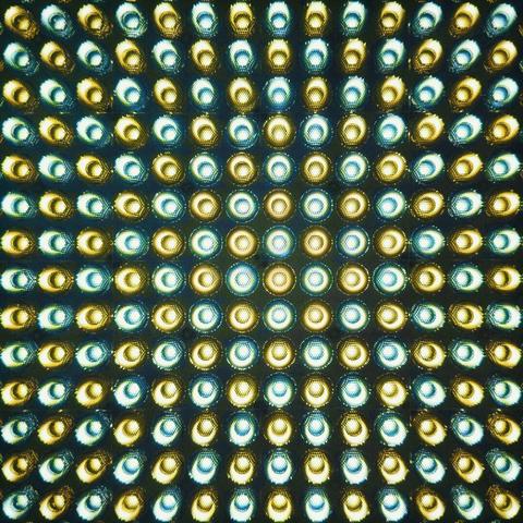 A square grid of tungsten and daylight LED bulbs shines brightly, filling the entire frame.