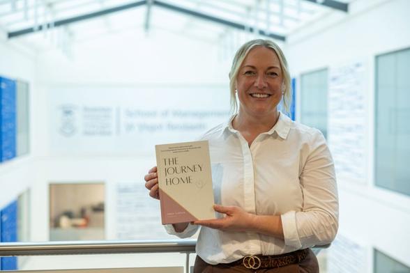 Emma Tamplin holding her book The Journey Home outside Swansea University.