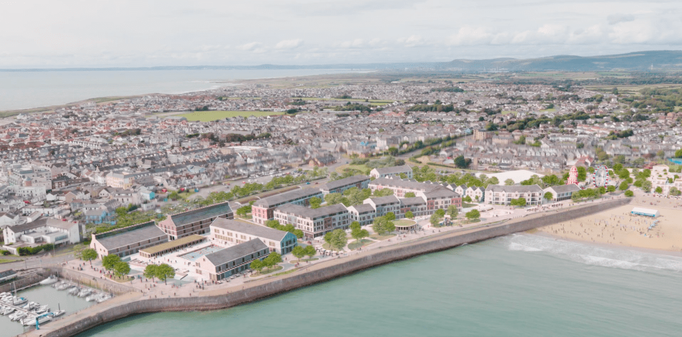 Aerial view of Porthcawl seafront with marina, beach, and amusement rides.