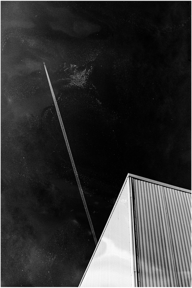 A plan with contrails flying diagonally across a speckled sky