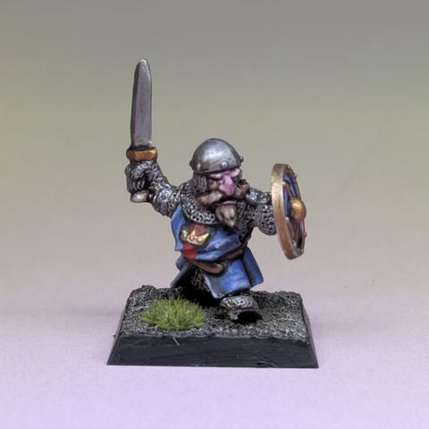 A dwarf holds a shield and sword. His blue tunic has a crown motif.