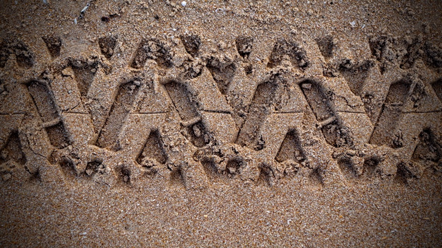 Ein grobstolliger Geländereifen hat im Sand seine Abdrücke hinterlassen, die aussehen wie eine in den Sand gedrückte Girlande...