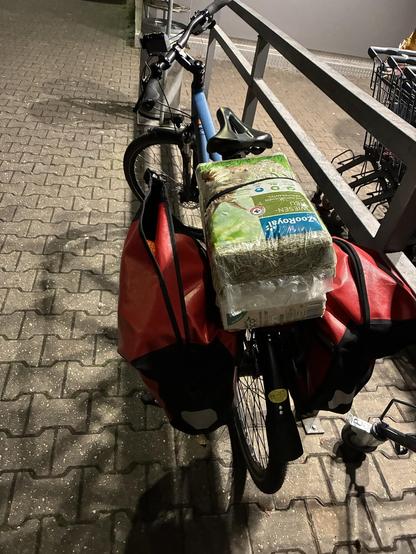 Mein blaues Gudereit Bike, bepackt mit zwei sehr vollen roten Ortlieb Taschen, einem Paket Streu und einem Paket Heu.