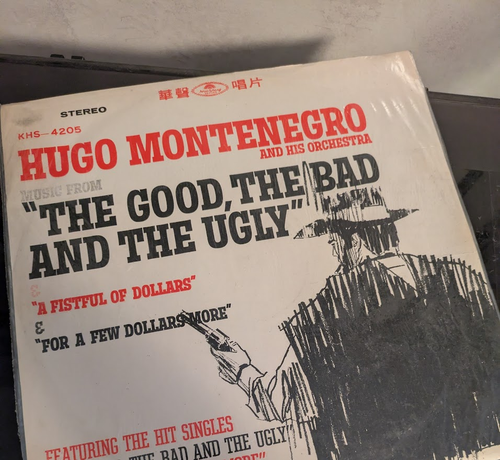 The cover to a Hua Sheng produced copy of a vinyl LP record. It features a scrawled, charcoal-like image of the back of a cowboy. It says, "Hugo Montenegro and his Orchestra". The next line reads, "Music from 'The Good, The Bad and the Ugly"