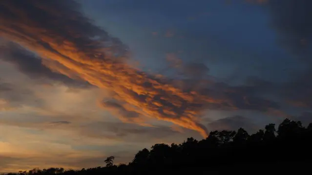Sonnenuntergang. Das Sonnenlicht bescheint von unten ein paar Wolken