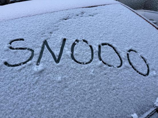 Napis “SNOOO” zrobiony palcem na ośnieżonej szybie samochodu.
