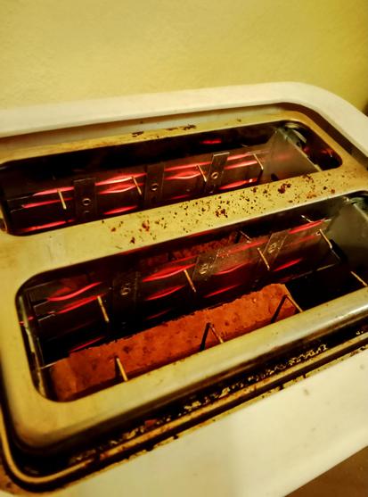 Filaments glow red as toast toasts in the toaster, round side down.