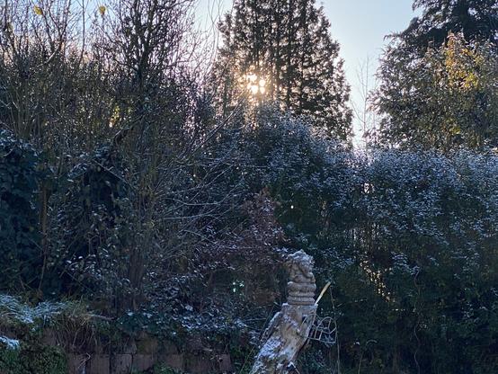 Die Momentaufnahme des Sonnenstandes um 10 Uhr zeigt in seitlicher Ansicht einen Berghang, bewachsen mit Büschen und Bäumen.
Der wolkenlos-blassblaue Himmel lässt einen schrägen Horizontverlauf erahnen und knapp darüber strahlt die tief stehende Herbstsonne durch die Zweige einer Zypresse.
Der Hang im schattigen Vordergrund ist mit Steinen befestigt und auf einem, in 1m Höhe abgeschnittenen Baumstamm thront ein steinerner Ganeesha nebst dem vergessenen Erntemesser über einem angeschraubten Gartenschlauchhalter.