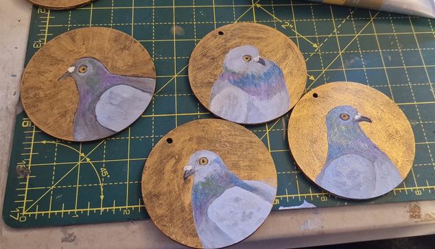 4 wooden circles for hanging on Xmas trees with pigeons painted on them.