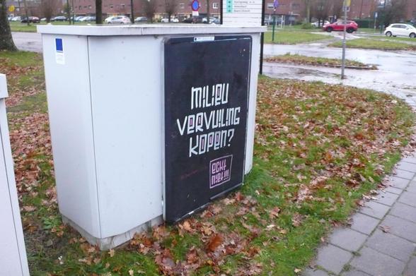 straatkastje op hoek op gras met herfst bladeren, verkeer op de achtergrond
Zwarte poster met in wit en roze letters, zie caption